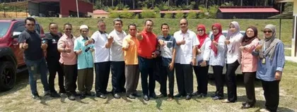 Rombongan pelawat dewasa bergambar di ladang, dengan rumah cendawan di belakang.
