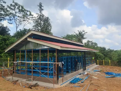 Rumah cendawan dalam pembinaan dengan rangka rak biru.